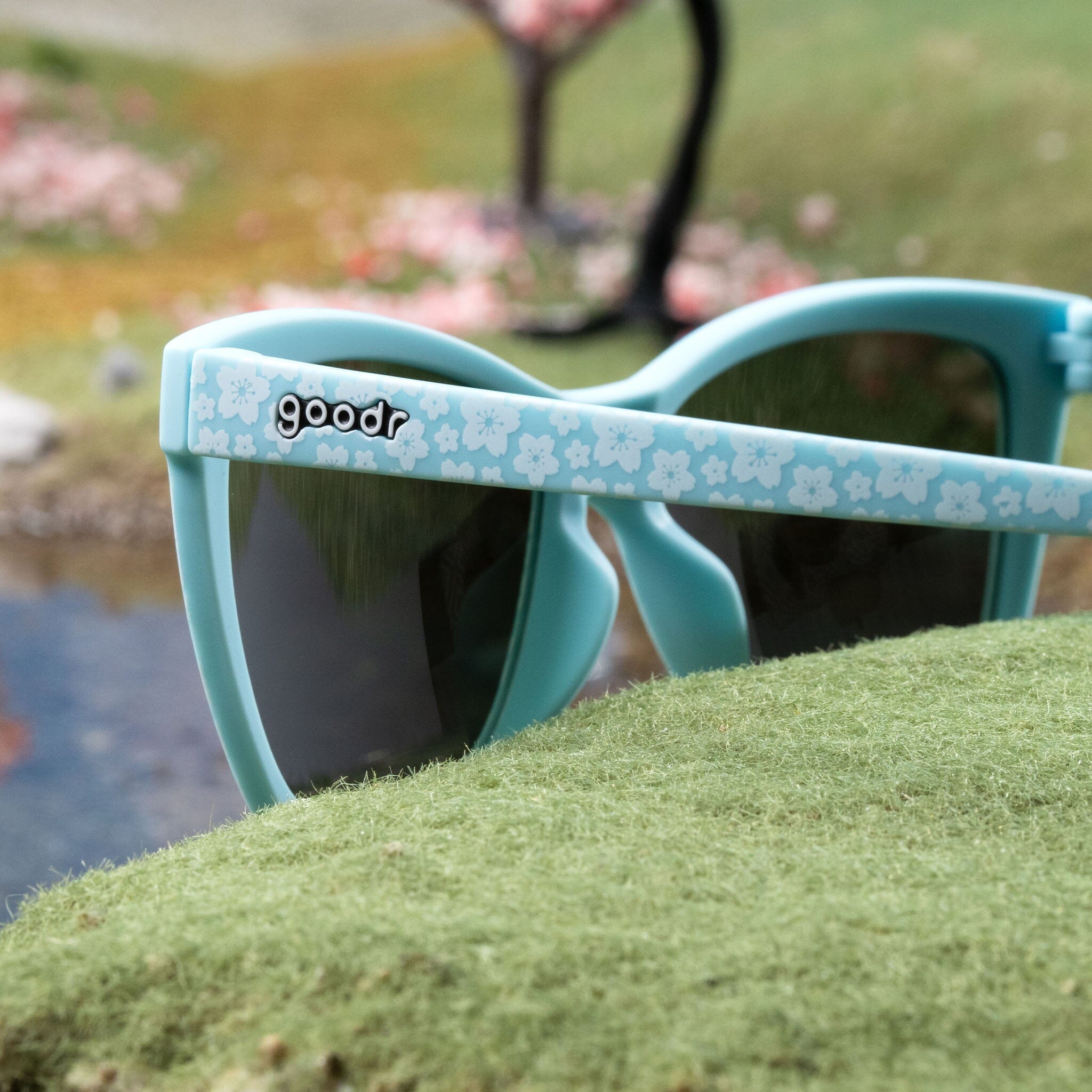 Light blue cherry blossom sunglasses photographed from behind, posed in a miniature cherry blossom tree landscape.